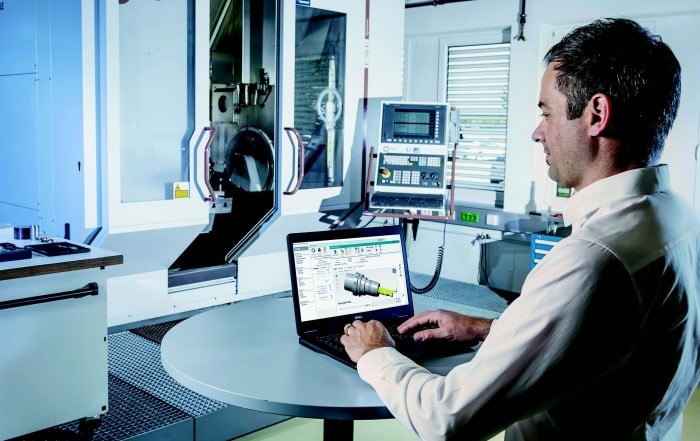 Mann vor Maschine mit Laptop und der Werkzeugverwaltunssoftware WINTool