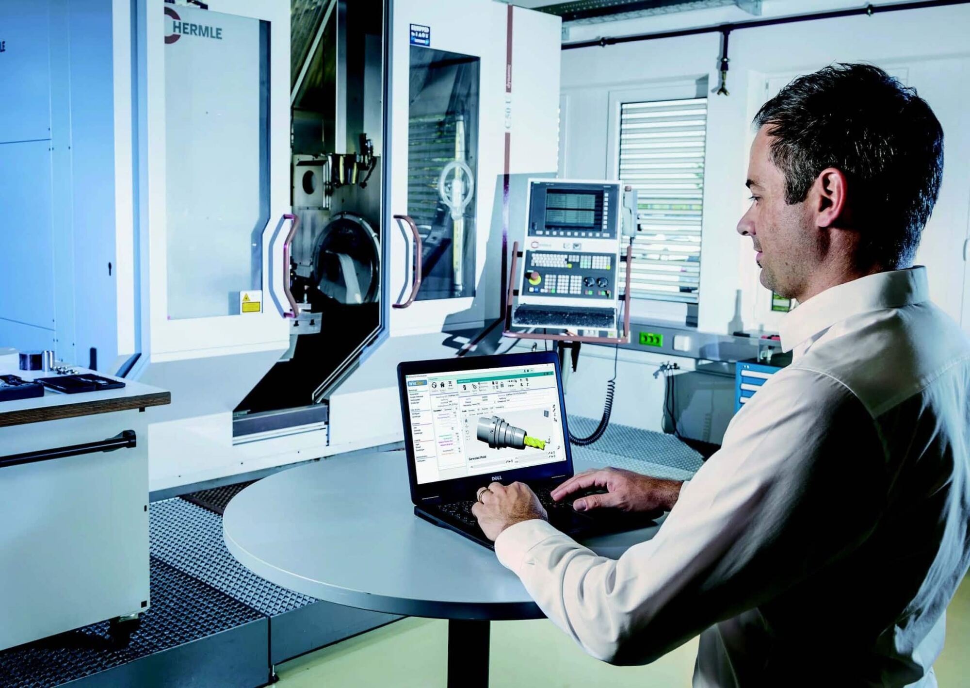 WINTool in Aktion Mann vor Maschine mit Laptop und der Werkzeugverwaltunssoftware WINTool